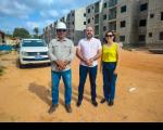 Imagem mostra em primeiro plano, três pessoas em pé diante de uma canteiro de obras. Ao fundo, imagens de prédios residenciais em construção.