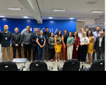 Foto mostra servidores e servidoras posicionados em pé no auditório da EJUD 16.