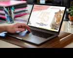 Foto de um notebook aberto sobre uma mesa. À esquerda, vê-se uma mão masculina de pele clara sobre o teclado. Na tela, vê-se a arte da expeosição.