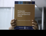 Arte feita com uma foto de uma pessoa negra segurando um livro: a capa tem a informação - Protocolo de Julgamento com Perspectiva Racial - CNJ