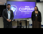 Foto mostra um homem e uma mulher posicionados um de cada lado de um painel escrito Prêmio Cooperari