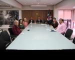 Foto mostra pessoas sentadas a mesa durante audiência de conciliação
