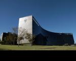 Foto da fachada do prédio do TST e do CSJT. Na base, vê-se campo gramado e, no topo, céu azul bem límpido.