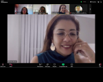 Foto de tela de computador mostrando videoconferência, com mulher clara de cabelos escuros (a palestrante) em destaque, ao centro. No topo, fotos de três mulheres e um homem como participantes.