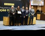 Foto mostra a juíza titular, Erika Guimarães Gonçalves e o diretor de secretaria, o servidor Noredim Oliveira Reuter Ribeiro Neto recebendo a certificação das mãos dos ministros do TST Maurício Godinho Delgado e Cláudio Mascarenhas Brandão