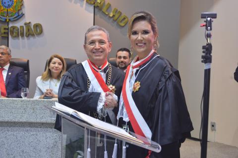homem de toga ao lado de mulher de toga em frente a uma tribuna  pousando para foto