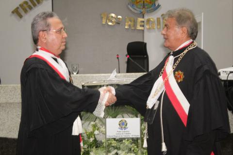 dois homens de toga em pé, um de frente para o outro, cumprimentando-se