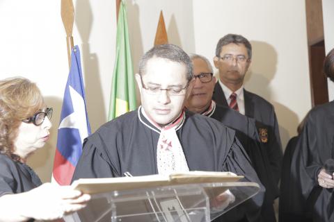homem de toga assinando documento frente a uma tribuna