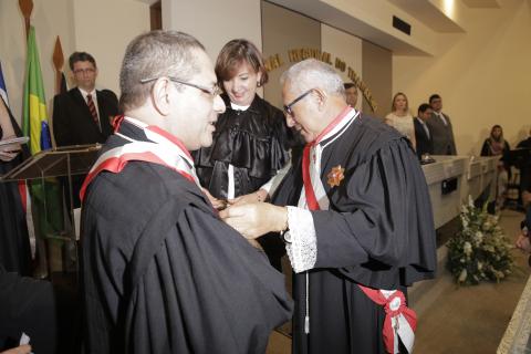 dois homens de toga em pé, um de frente para o outro, no ato de entrega de medalha