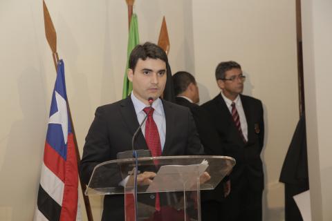 Homem de terno em frente a um tribuna discursando
