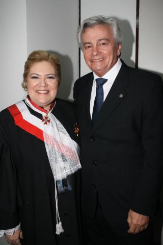 Mulher ao lado de um homem, ambos de toga pousando para foto.