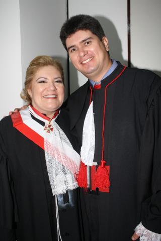 Mulher ao lado de um homem, ambos de toga pousando para foto.