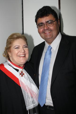 Mulher de toga ao lado de um homem de terno,  pousando para foto.