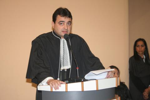 homem de toga discursando em pé em frente a uma tribuna