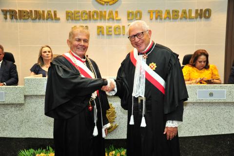dois homens de toga em pé, cumprimentando-se e pousando para foto.