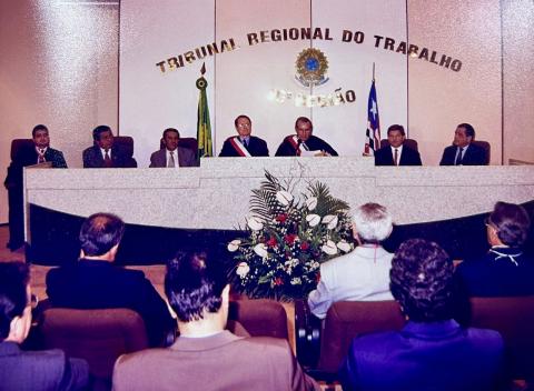 pessoas em frente a uma mesa de honra, sentadas, com várias autoridades